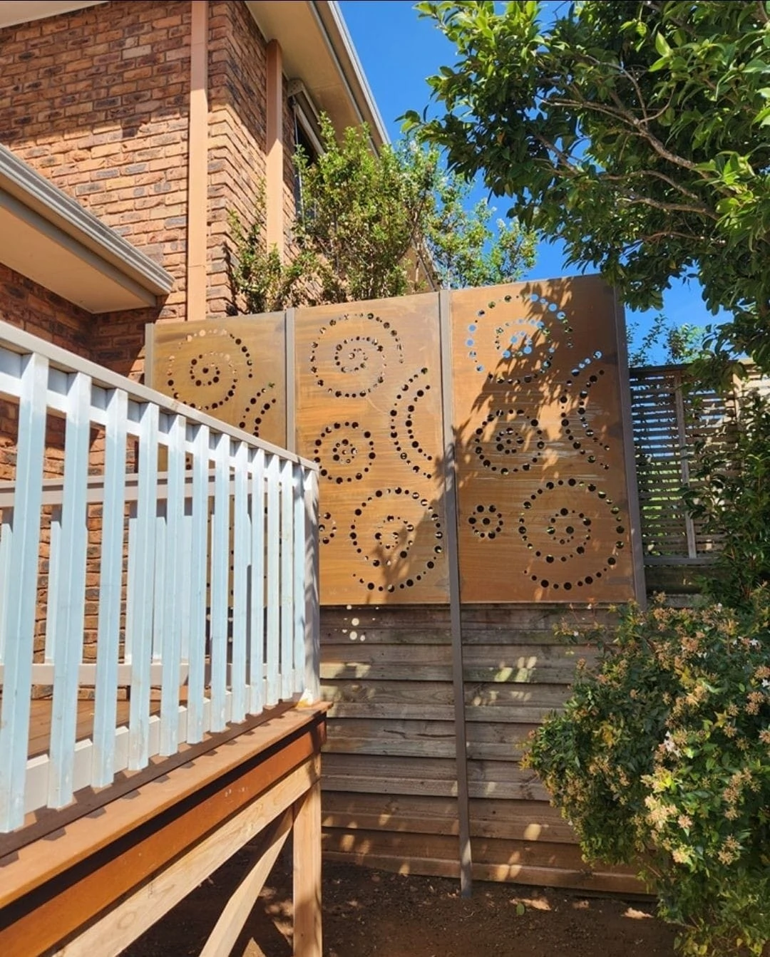 Decorative timber screen, steps and balustrade beside a brick home