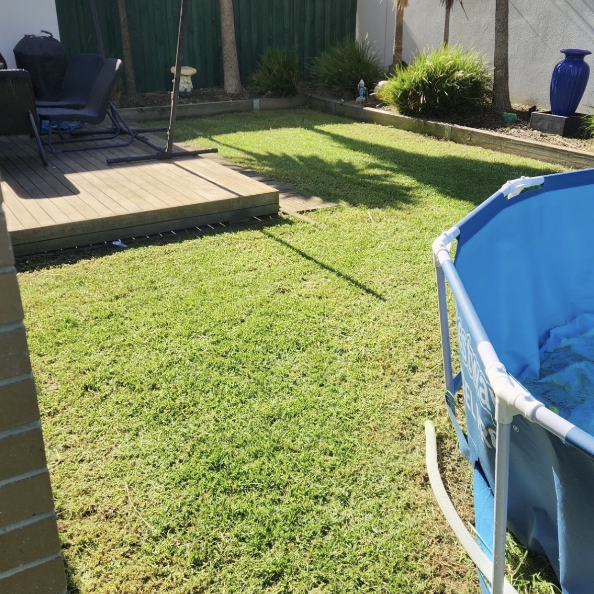 After mowing: the lawn cut beside the same timber deck and above-ground pool